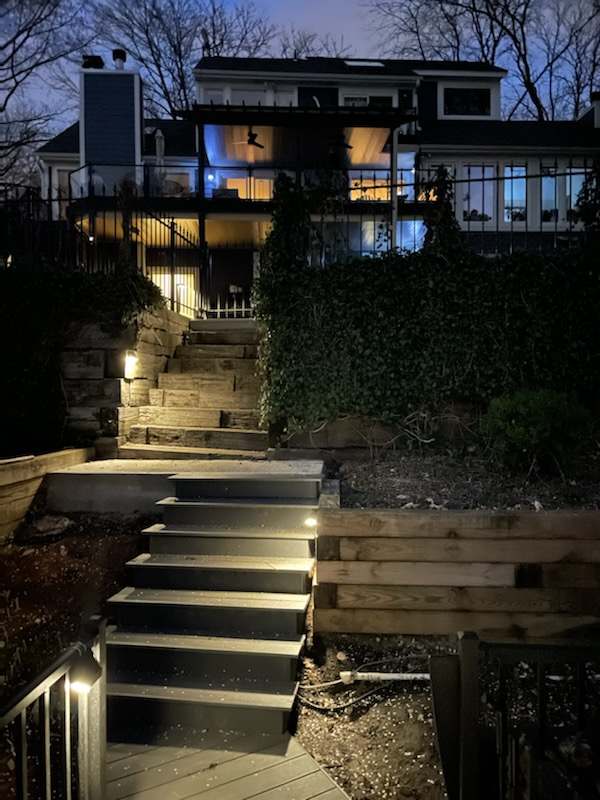 The lit stair rising from the water toward the house at night