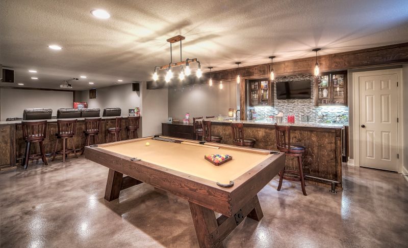 Open lower level with a wet bar and a pool table under recessed lighting
