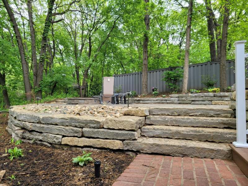Dry stacked limestone steps & walls terracing the slope beside the patio