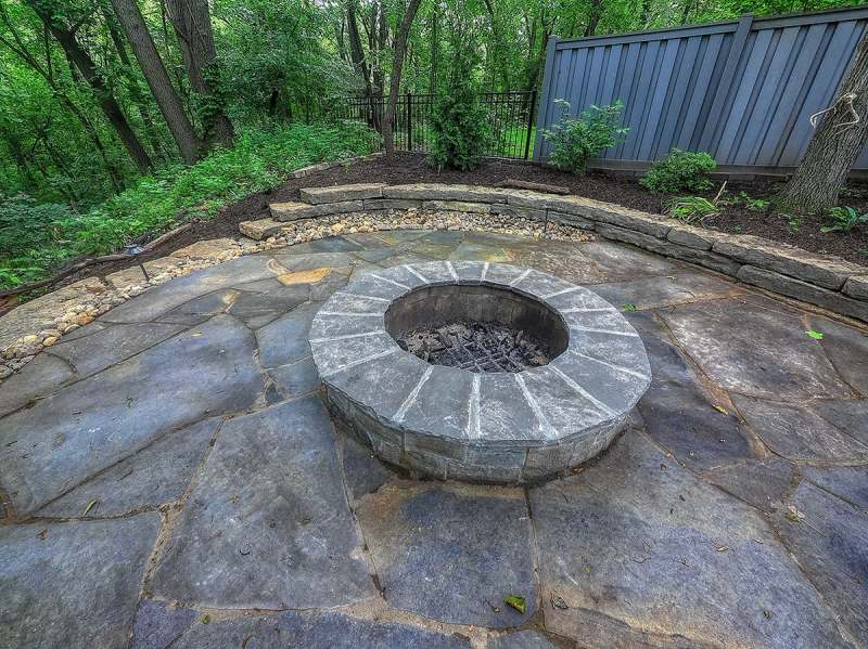 The wood burning fire pit with its stone cap, set into the flagstone patio