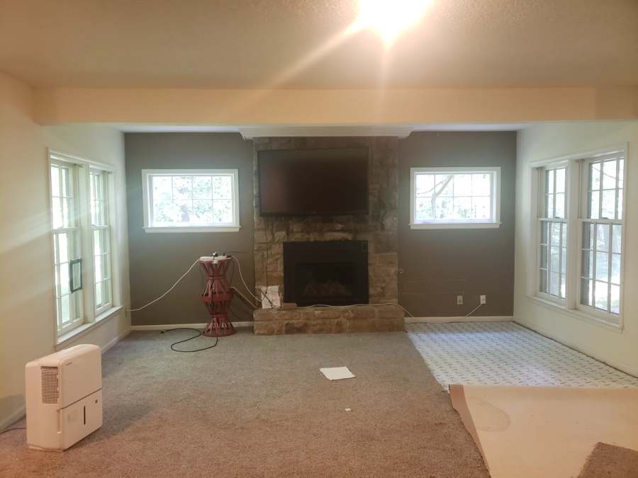 The basement family room before: wall to wall carpet, dark walls & the stone fireplace