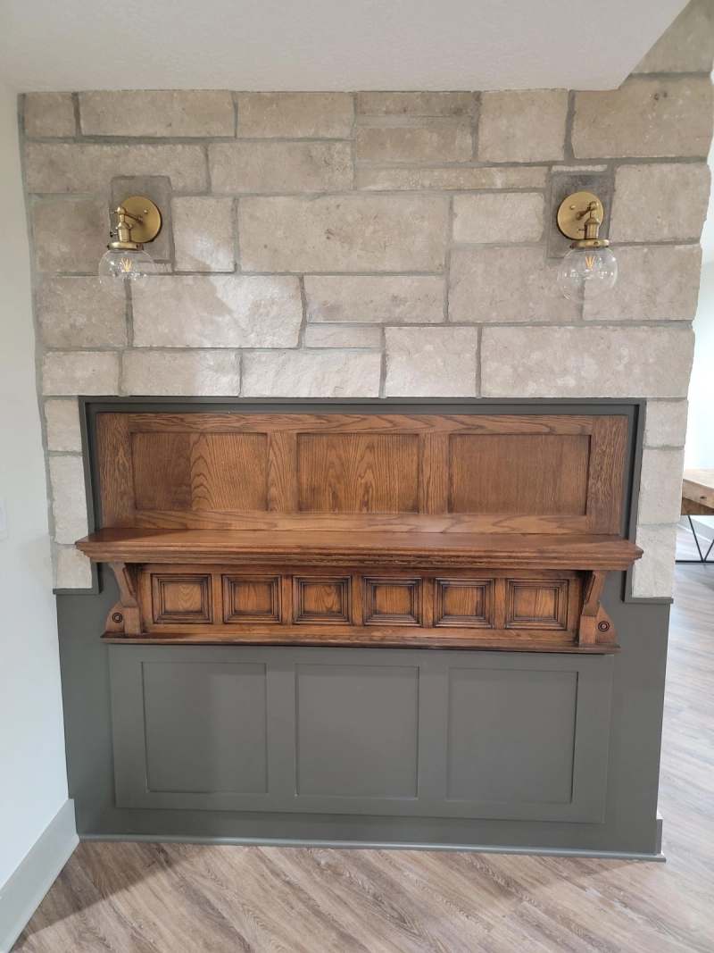 An antique carved back bar set into the stone wall between brass sconces