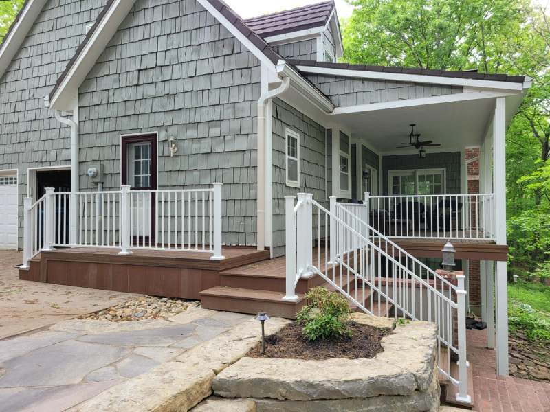 Composite deck steps & white rails leading down to the flagstone & stone walls
