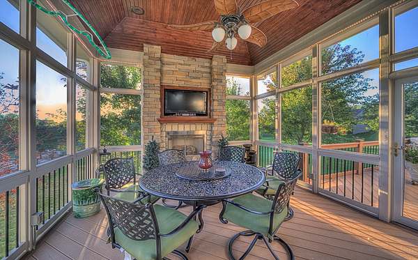 Screened porch with stone fireplace and tongue-and-groove ceiling at dusk — All Under One Roof, Kansas City
