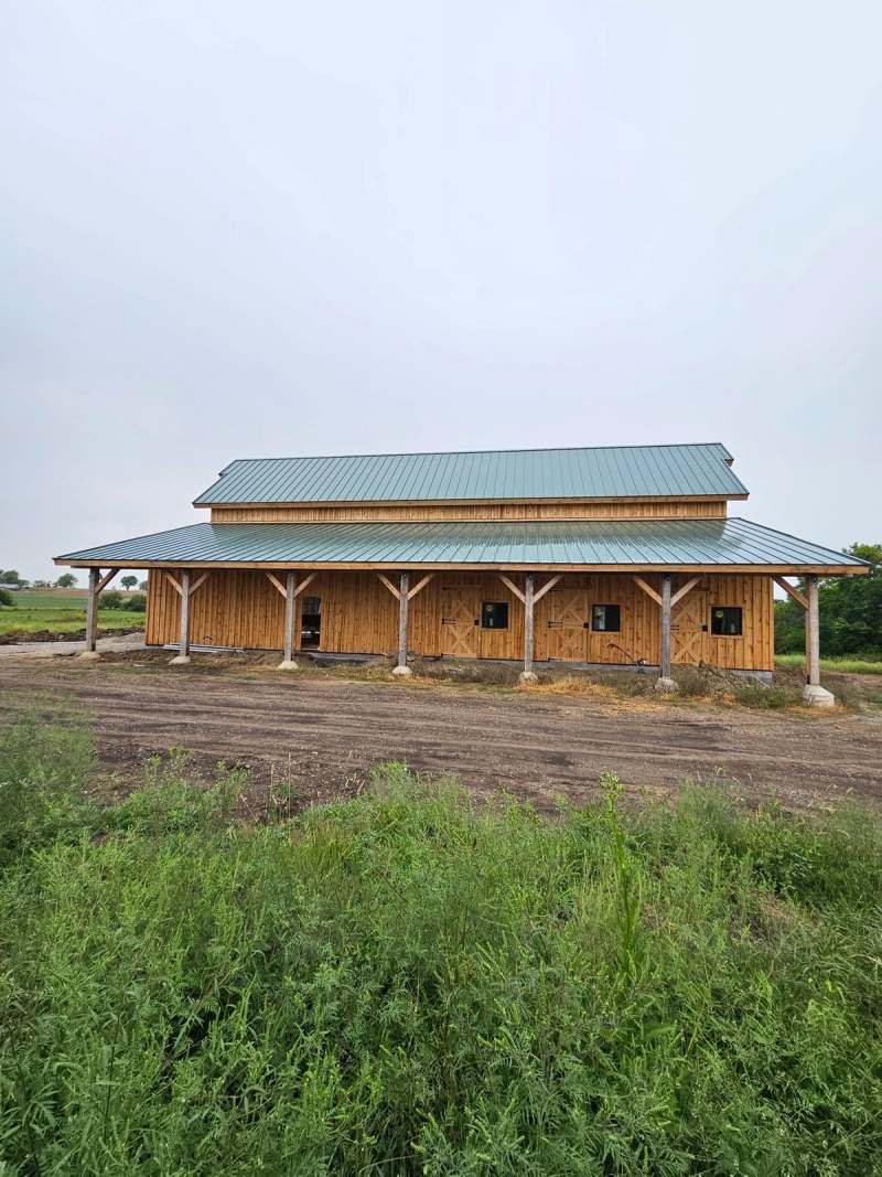 The full length covered porch on timber posts, seen across the prairie grass