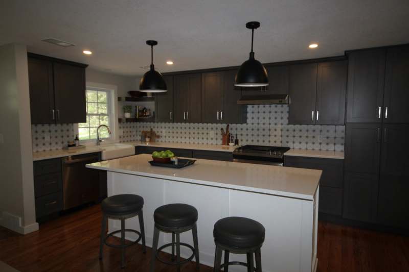 Charcoal shaker cabinets running to the ceiling behind the island, with a patterned tile backsplash & open shelving