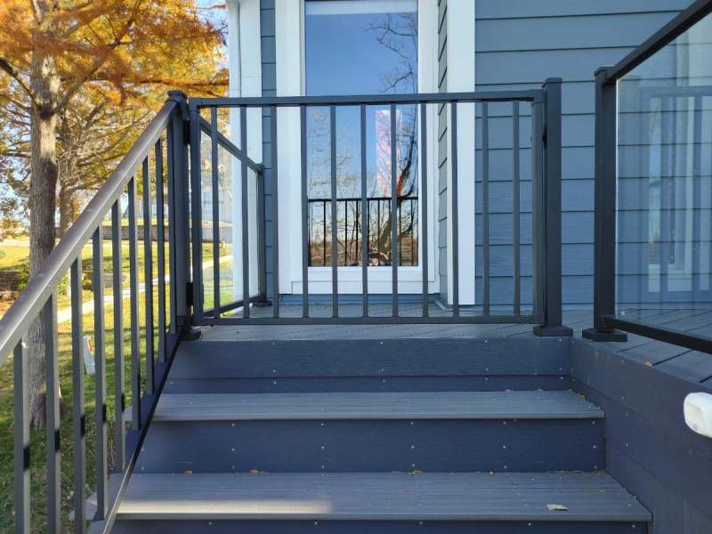 Deck steps at the house with black aluminum rails & a glass panel section