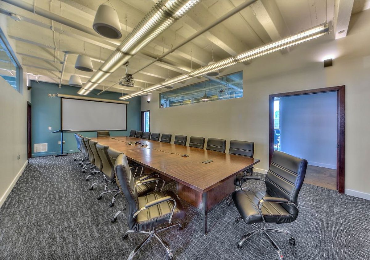 Finished commercial conference room with a long boardroom table in a downtown Kansas City office built by All Under One Roof