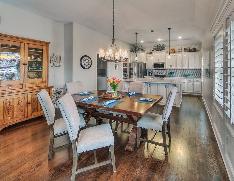 Kitchen opening directly onto a dining area with pendant lighting and hardwood floors