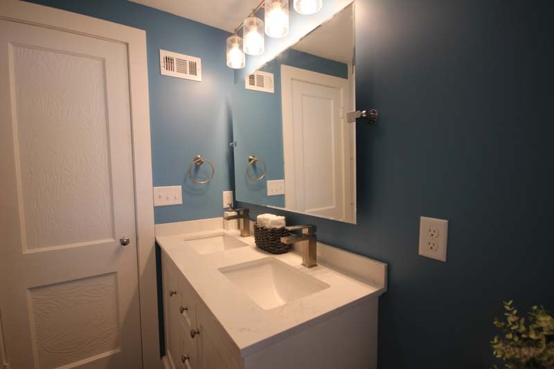 Hall bath vanity with a quartz top, brushed nickel faucets & blue painted walls