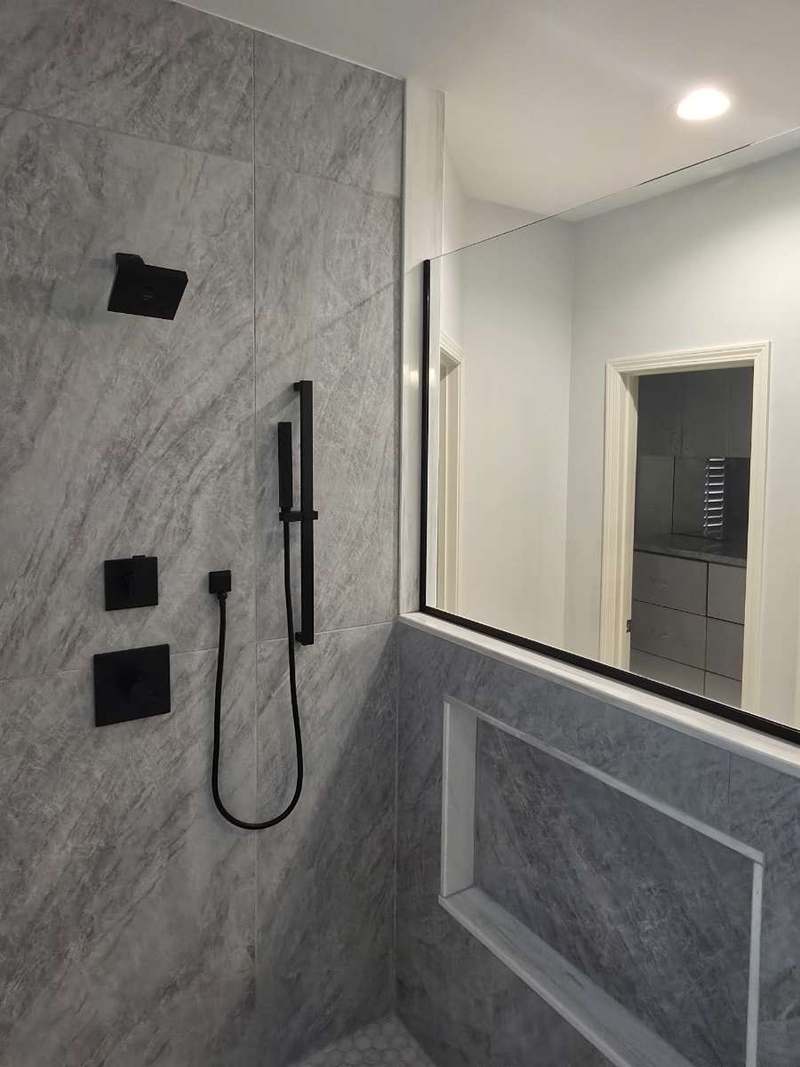 Matte black rain head, hand shower on a slide bar & thermostatic valves set into the large format shower tile