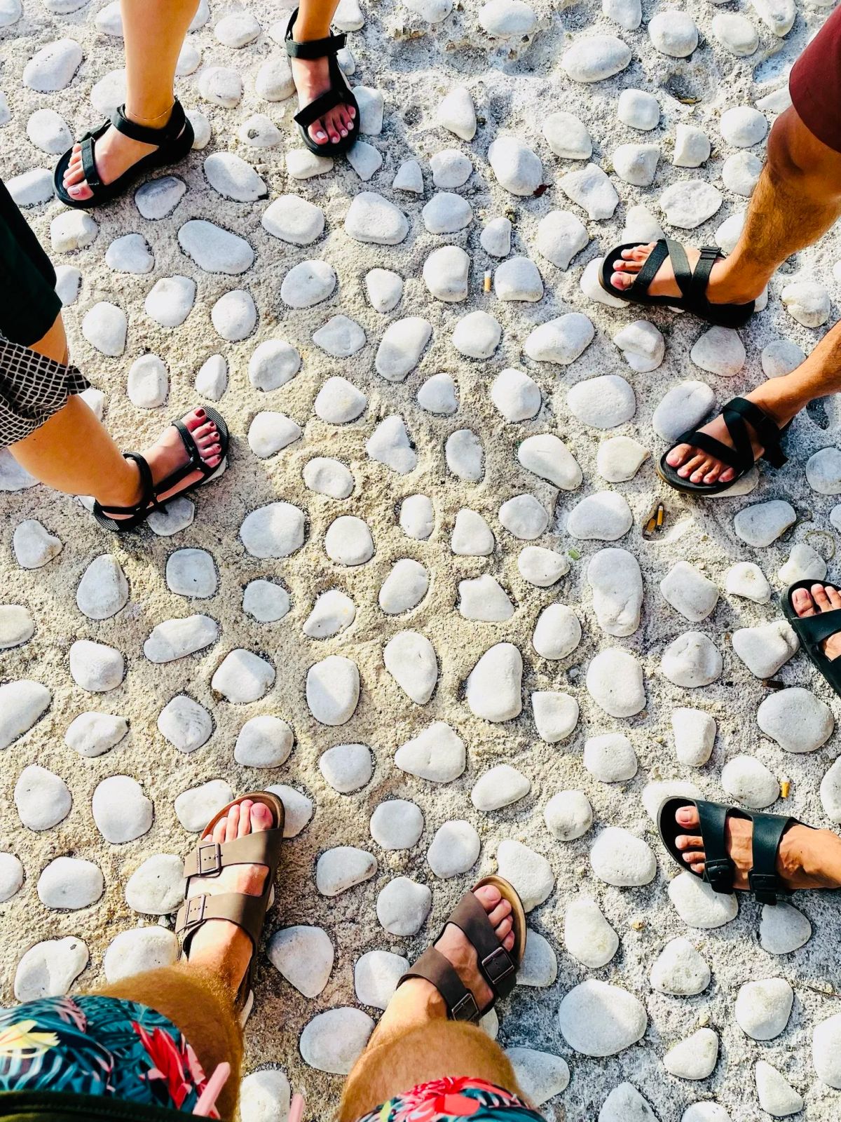 Looking down at feet on the smooth pebbles of a Greek beach