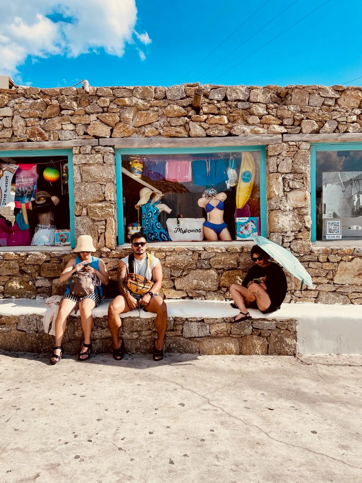 Three friends sitting outside a beachside shop in Mykonos