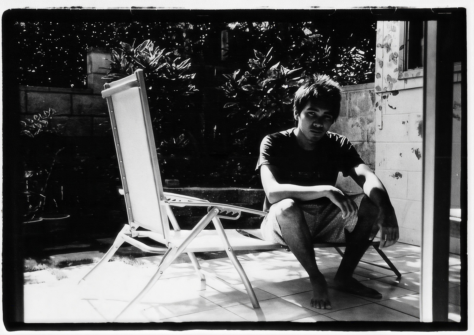 Male sitting on a lounge chair in black and white film photo.