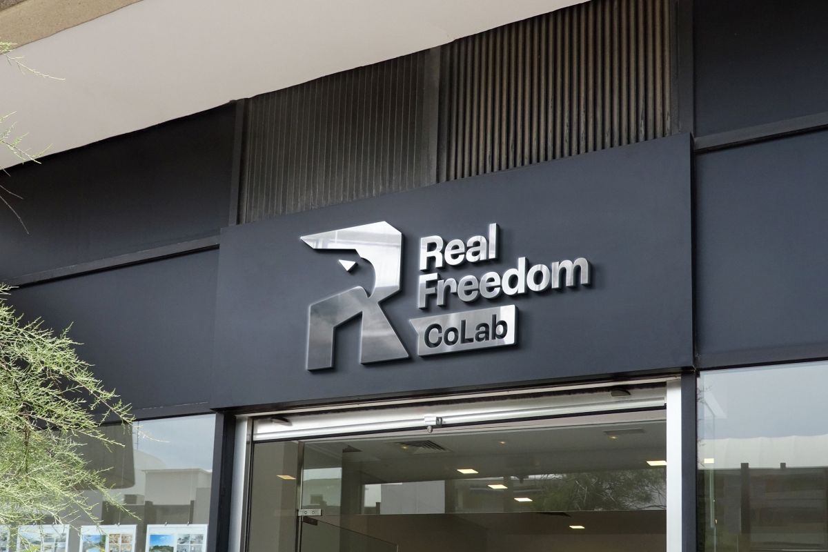Real Freedom CoLab eagle logo as brushed metal storefront signage mockup