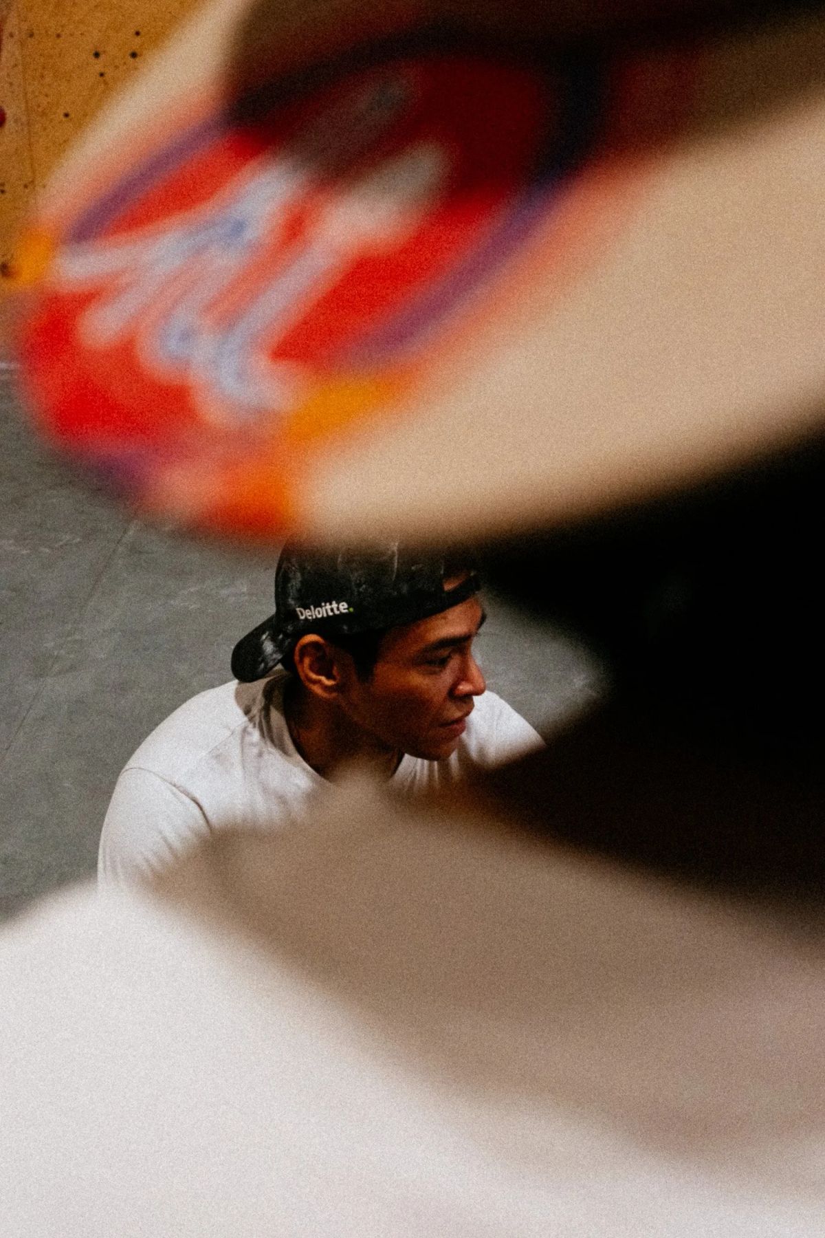 Climber in a backwards cap framed between out-of-focus climbing wall volumes