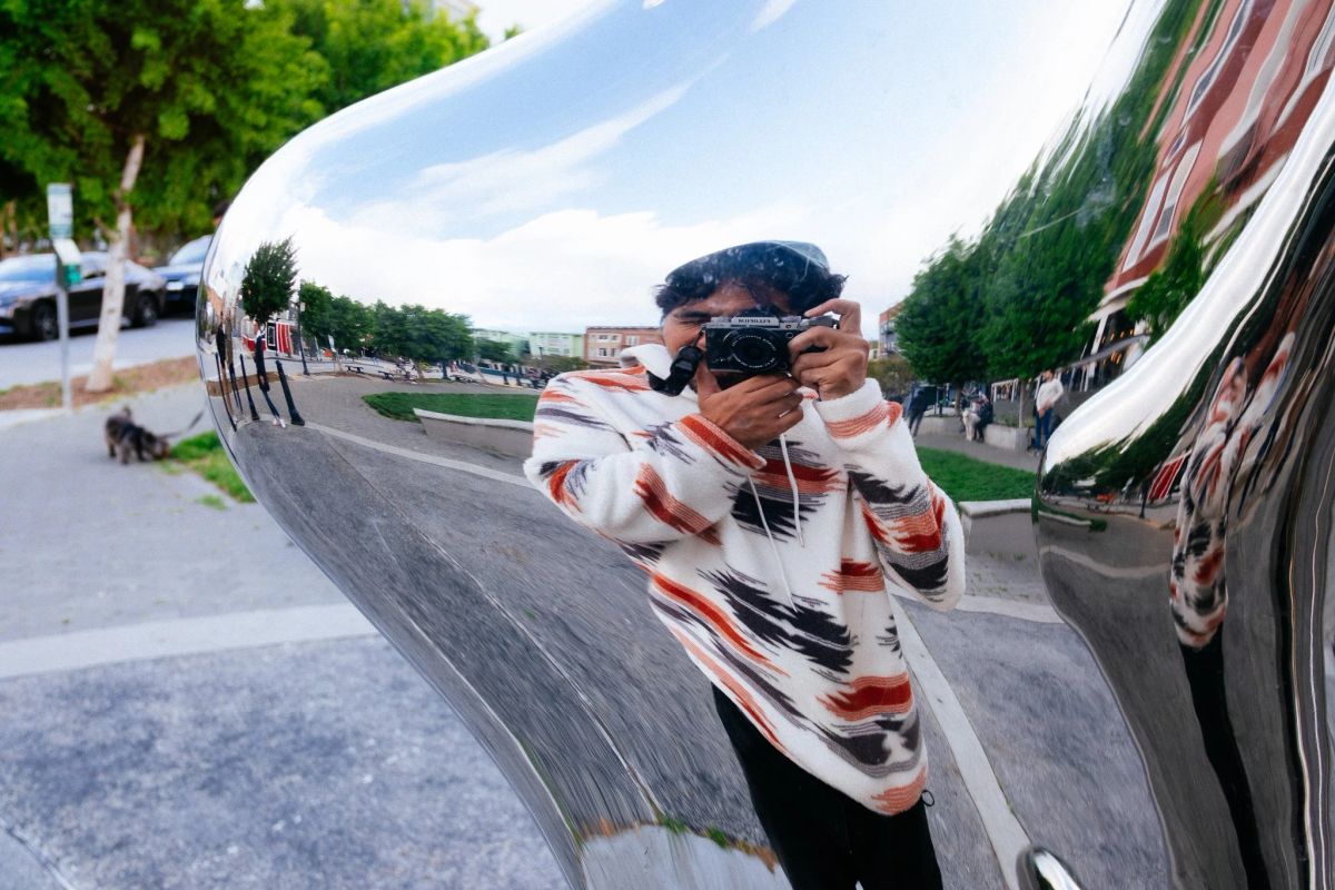 Mark photographing his reflection with a Fujifilm camera in a mirrored chrome sculpture in Hayes Valley
