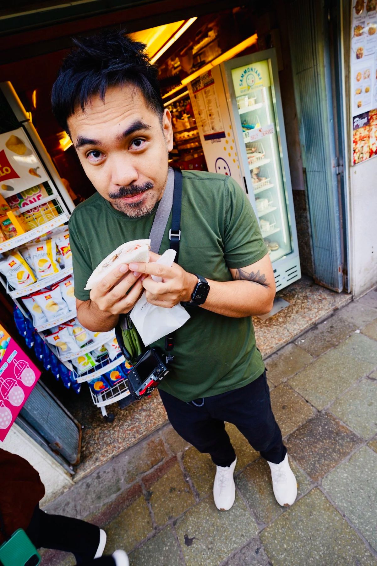 A man eating a tramezzino sandwich outside a Venice snack bar
