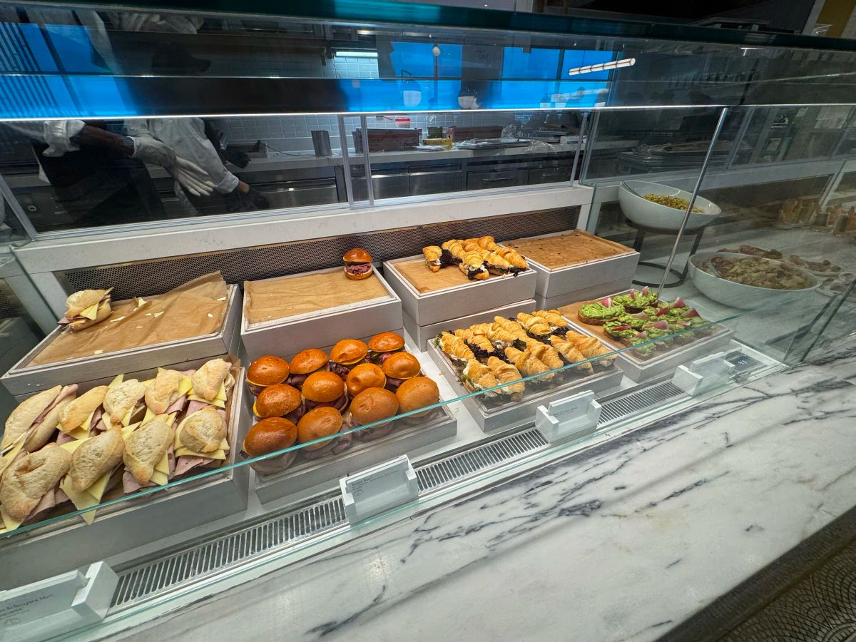 A lounge buffet case filled with sliders, croissant sandwiches, pastries and avocado toasts
