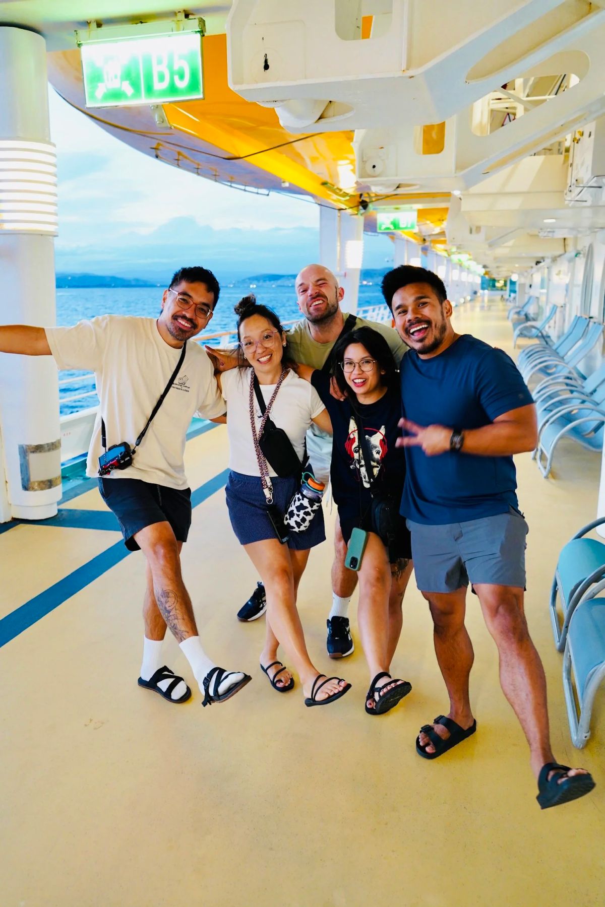 Five friends striking dance poses on the cruise ship deck at dusk