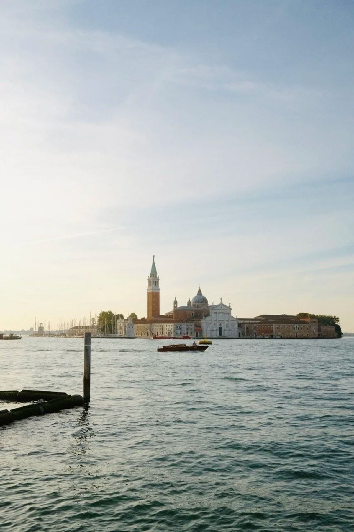 San Giorgio Maggiore's bell tower and church across the Venice lagoon at dusk, a boat crossing