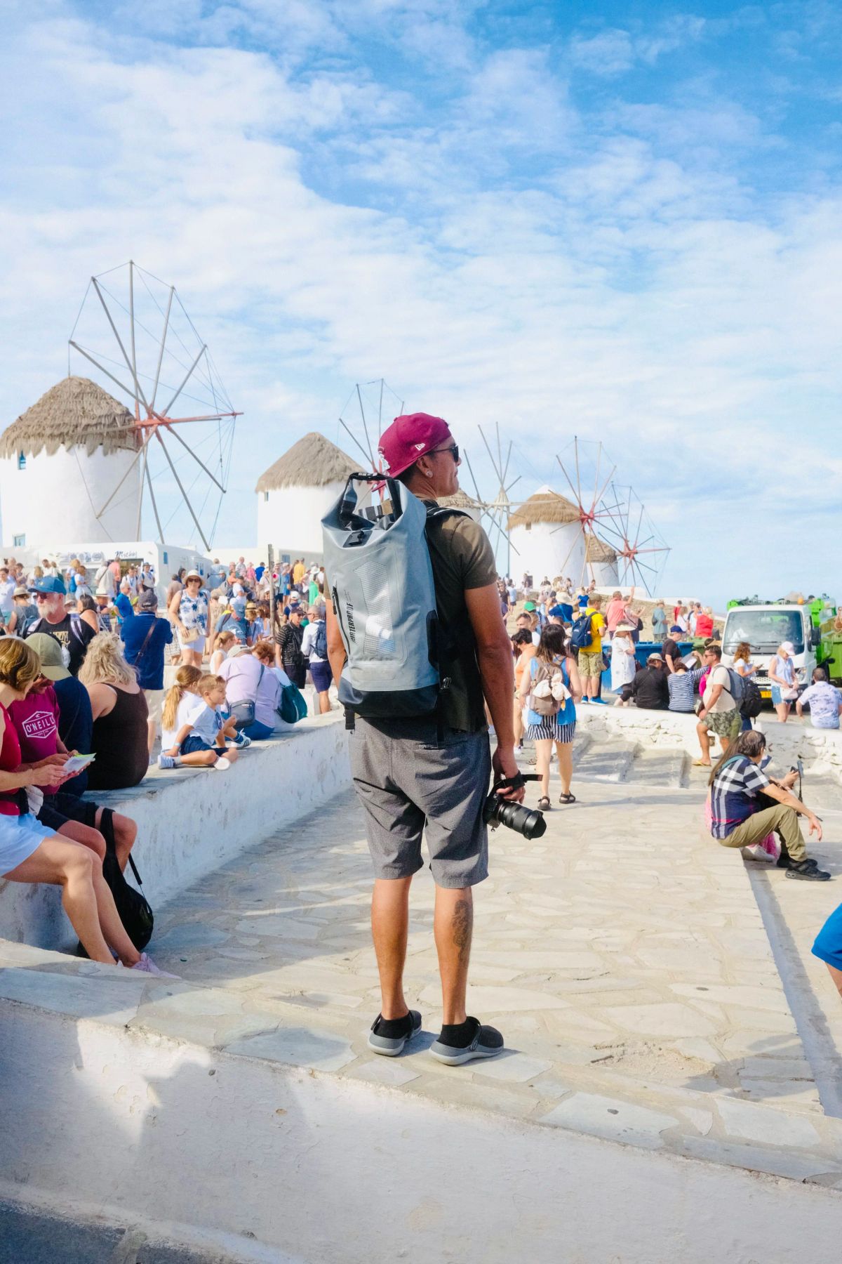 A man with a backpack standing near the windmills of Mykonos