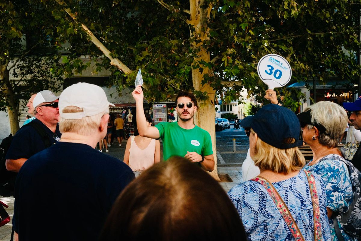 Tour guide holding up a numbered paddle for the group on an Athens street