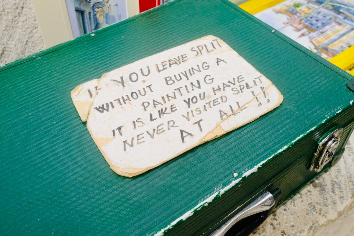 Handwritten sign in Split saying leaving without buying a painting is like never visiting