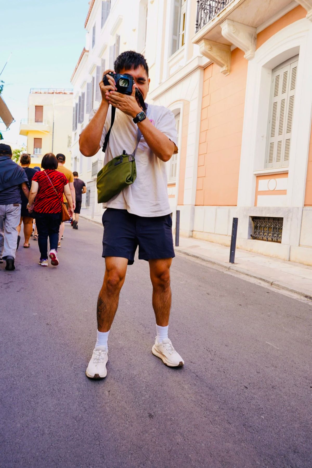 A man taking a photo with his camera on an Athens street