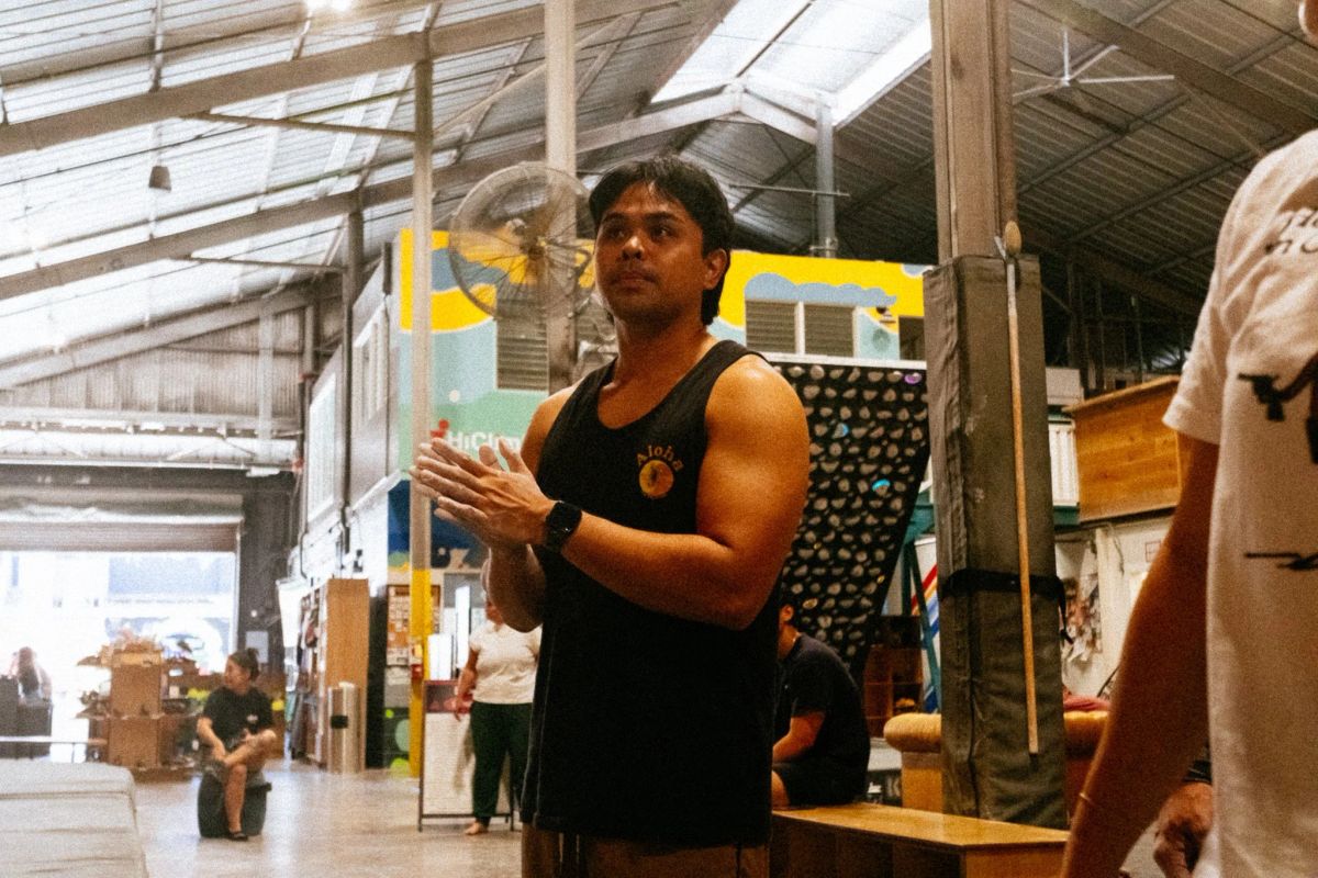 Climber in an aloha tank top clapping chalked hands inside a Honolulu climbing gym