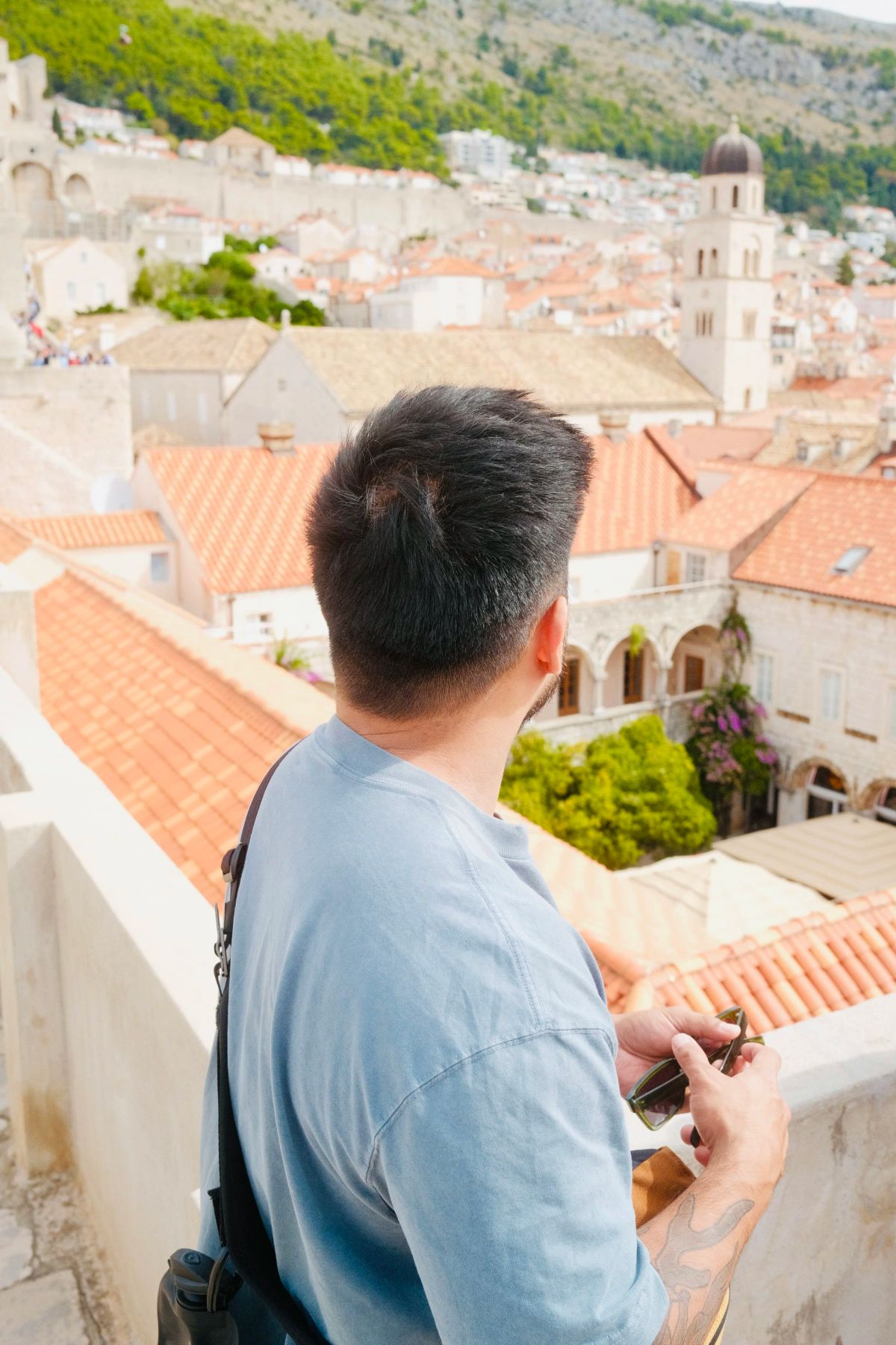 A man looking out over Dubrovnik's terracotta rooftops from the city walls