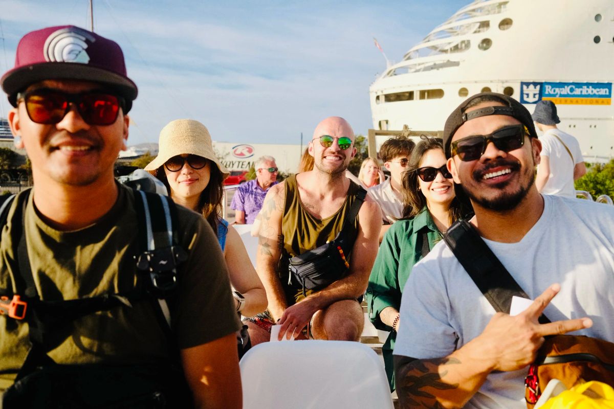 Friends on an open-air boat with a Royal Caribbean cruise ship behind them
