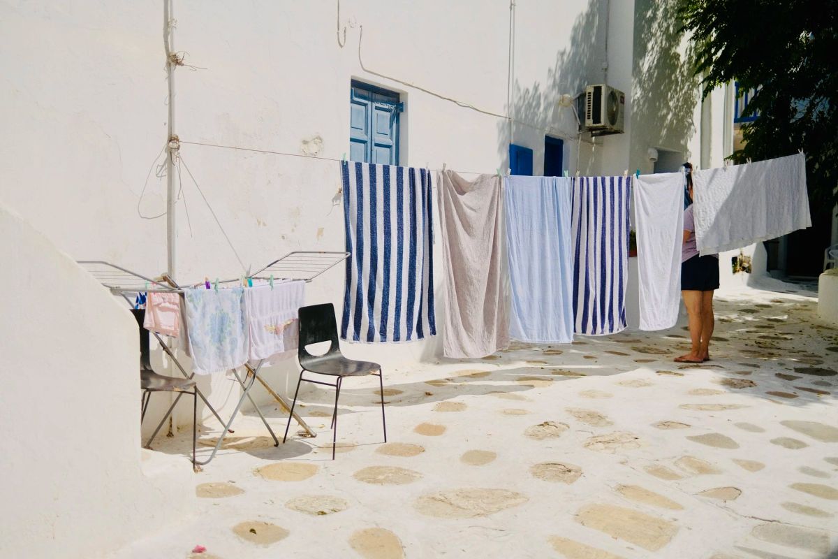 Laundry hanging between whitewashed buildings in a Mykonos alley