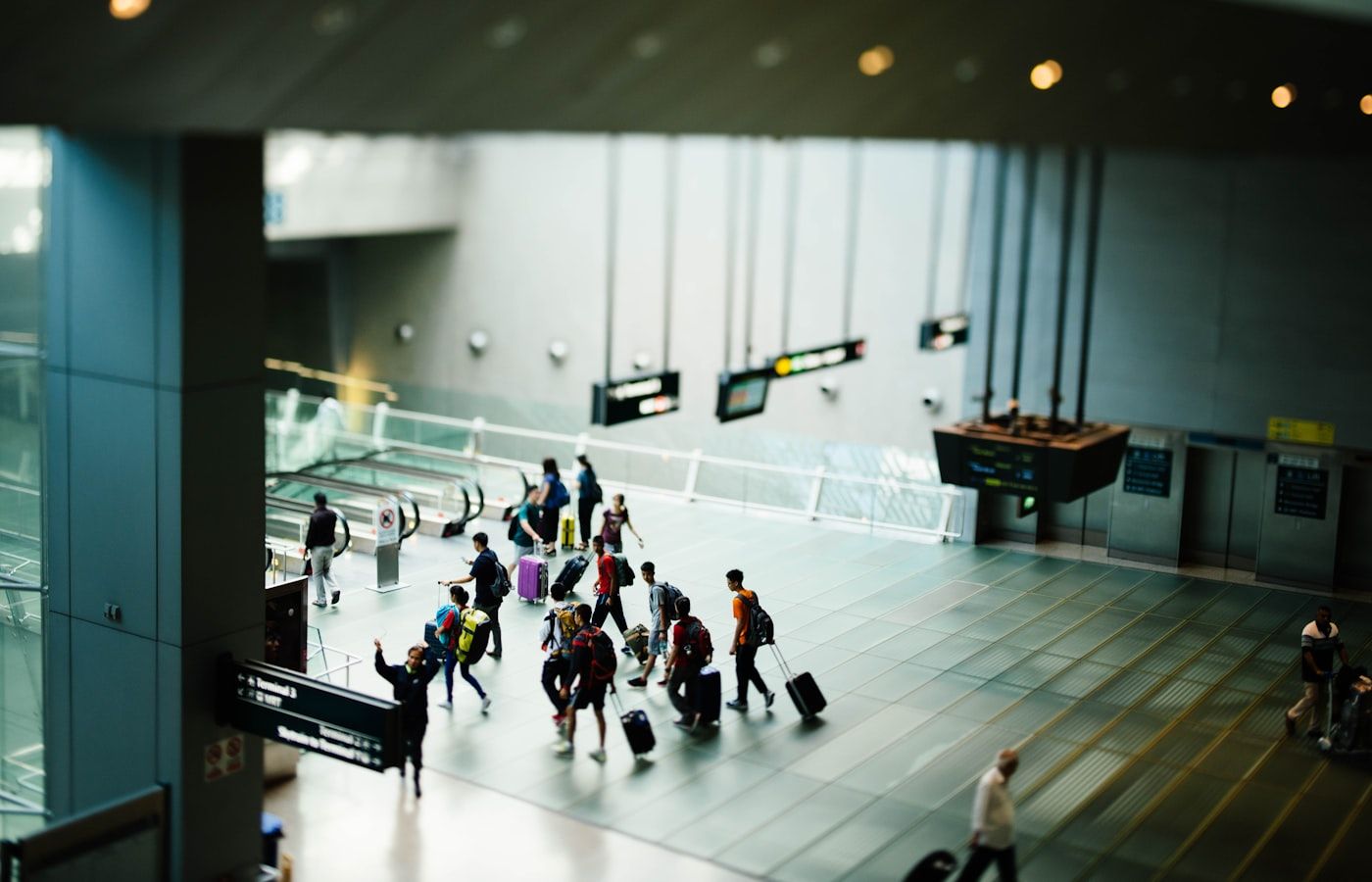Travelers with luggage walking through an airport terminal right after landing