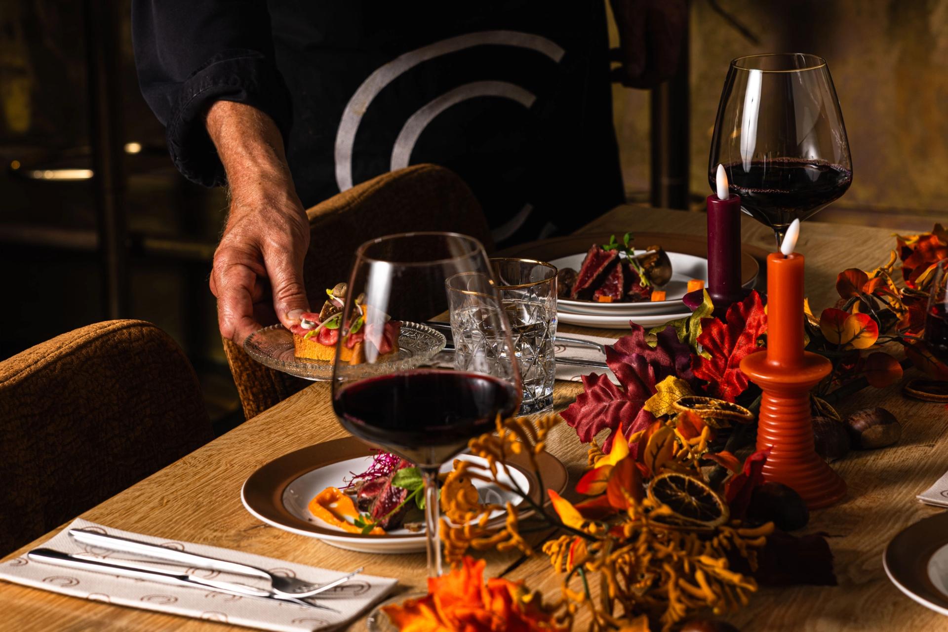Gasten proosten met rode wijn en bier boven een tafel vol hapjes