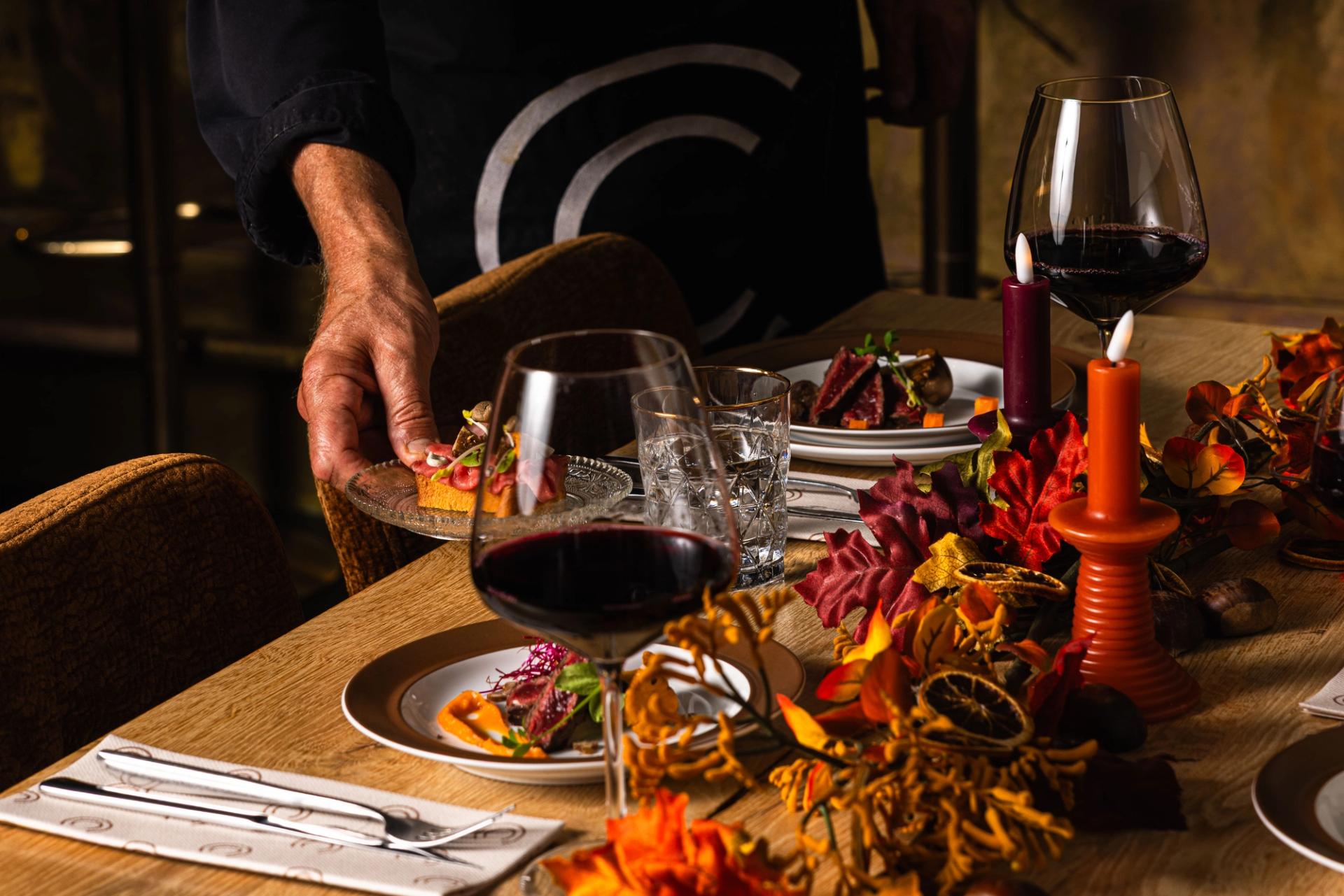 Gasten proosten met rode wijn en bier boven een tafel vol hapjes