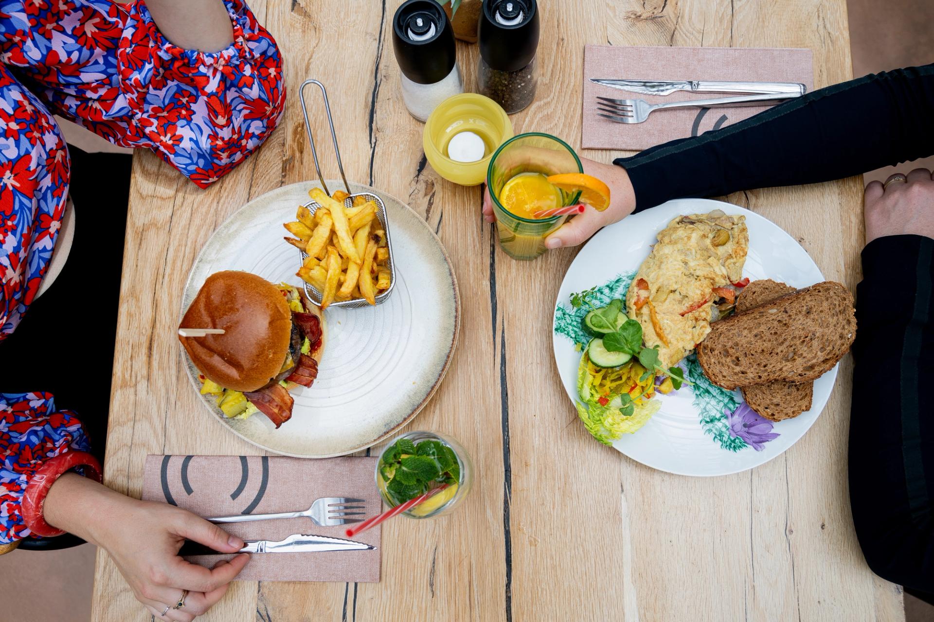 Twee gasten lunchen met een burger en een omelet bij La Cocotte in Hoogvliet Rotterdam