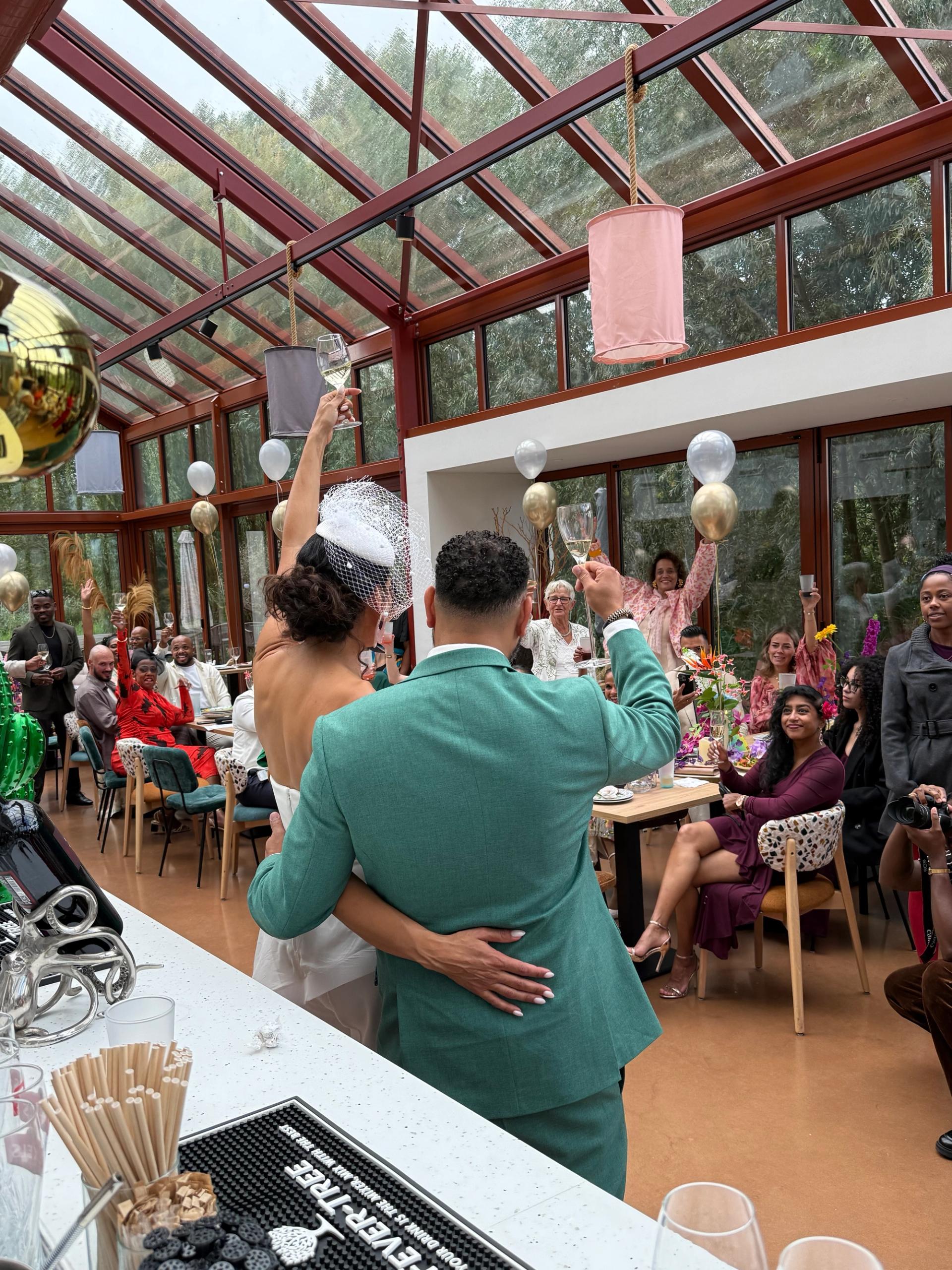 Proostende gasten in de Kas tijdens een bruiloft met ballonnen en cava.