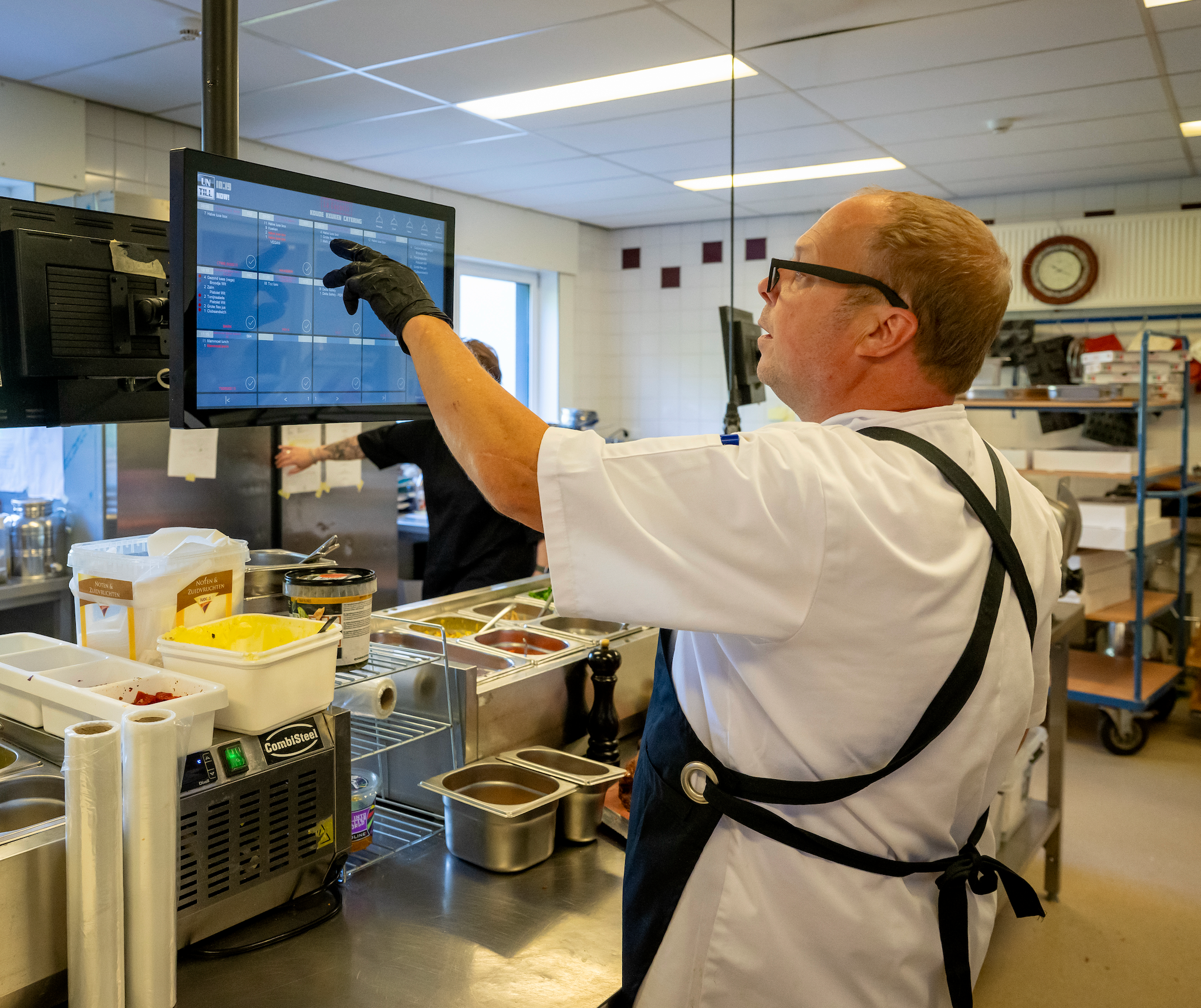 René van de bedrijfscatering bekijkt de bestellingen op het keukenscherm in de keuken van La Cocotte in Hoogvliet