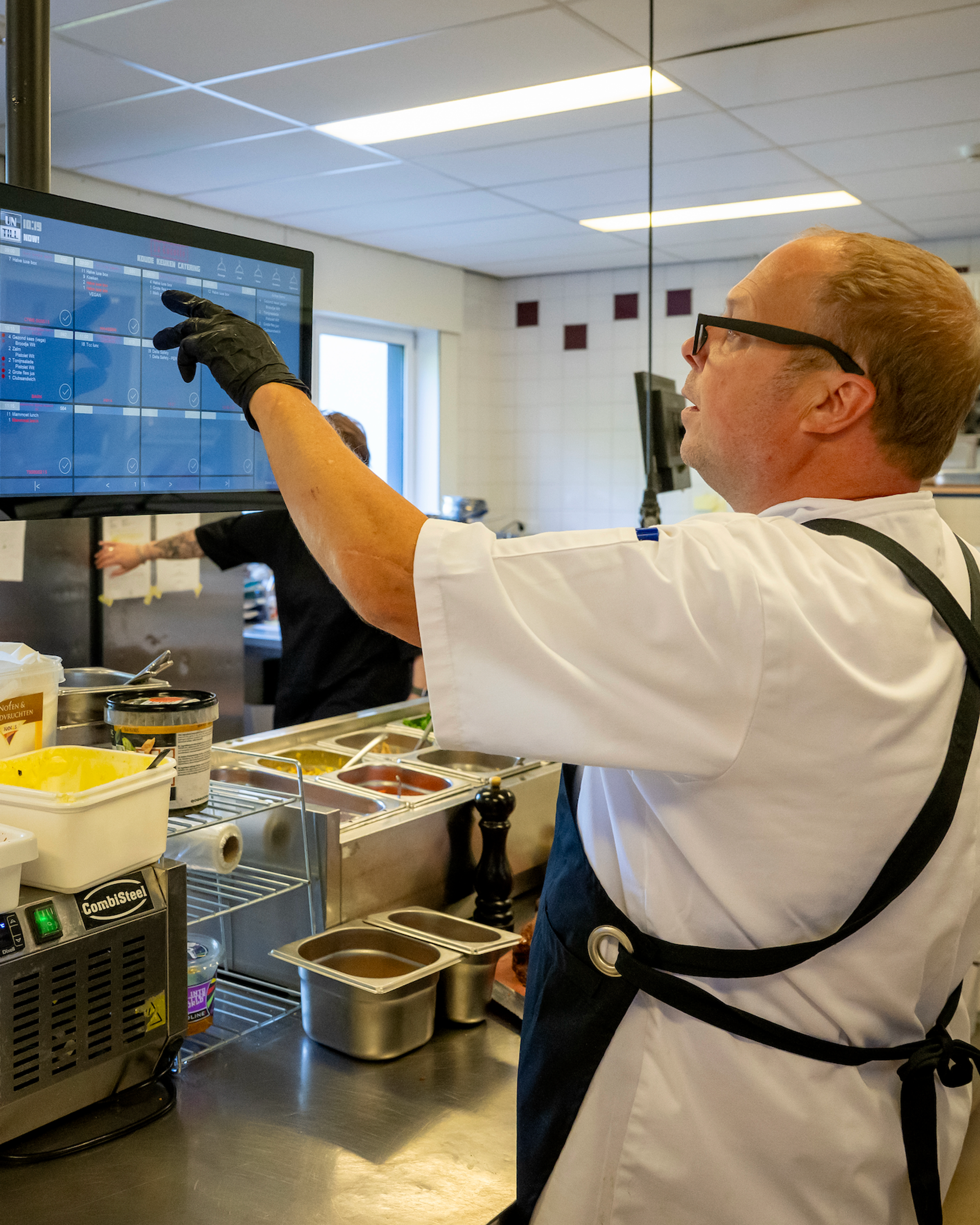 René van de bedrijfscatering bekijkt de bestellingen op het keukenscherm in de keuken van La Cocotte in Hoogvliet