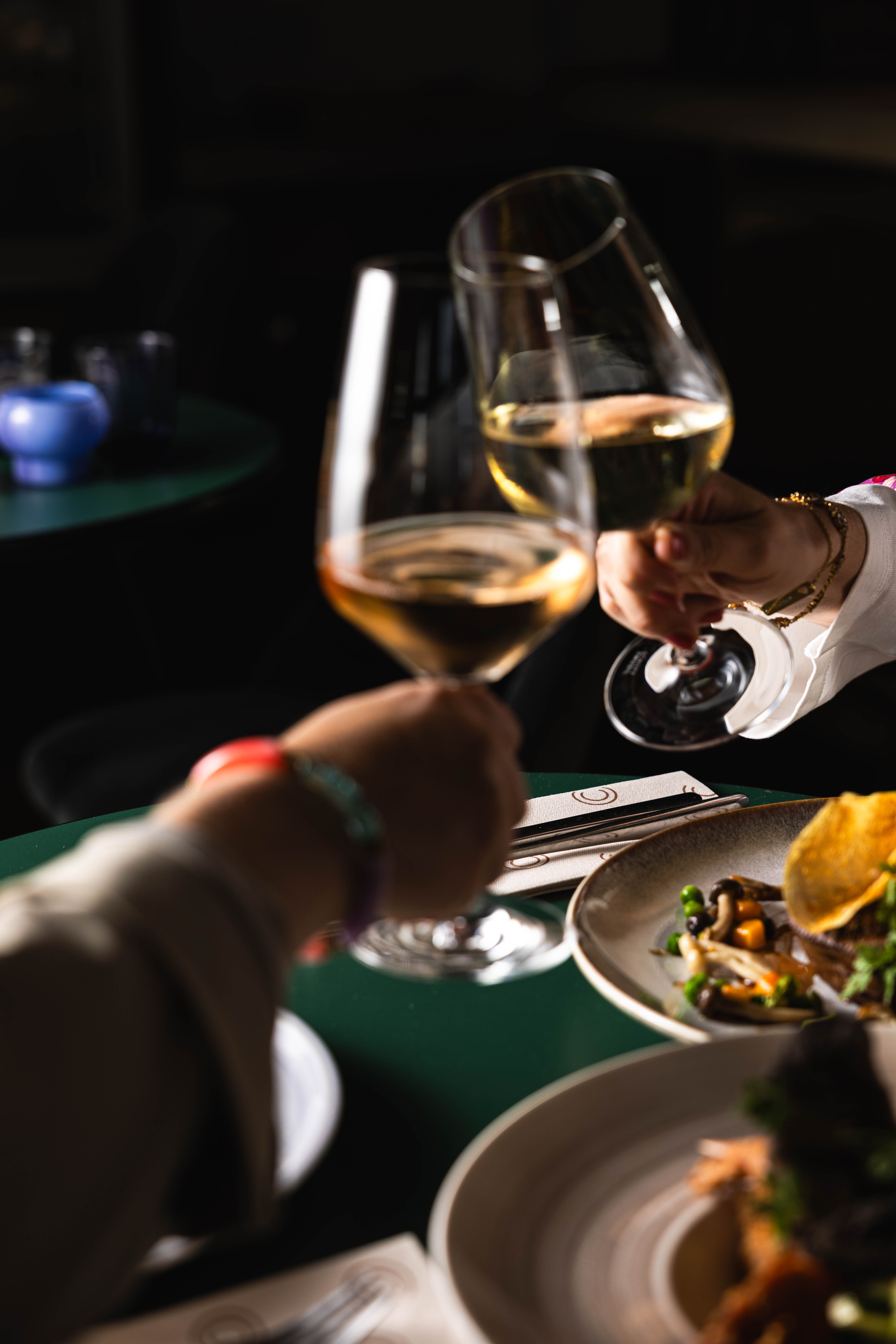 Twee gasten proosten met witte wijn aan tafel bij La Cocotte in Hoogvliet.