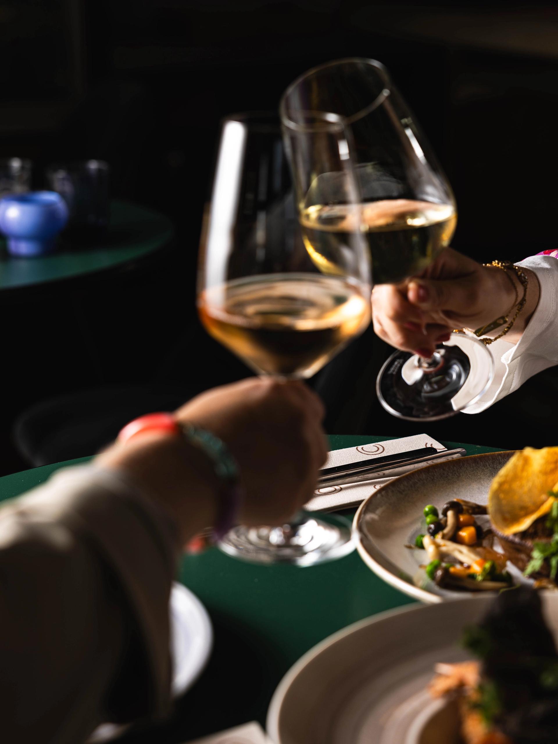 Twee gasten proosten met witte wijn aan tafel bij La Cocotte in Hoogvliet.
