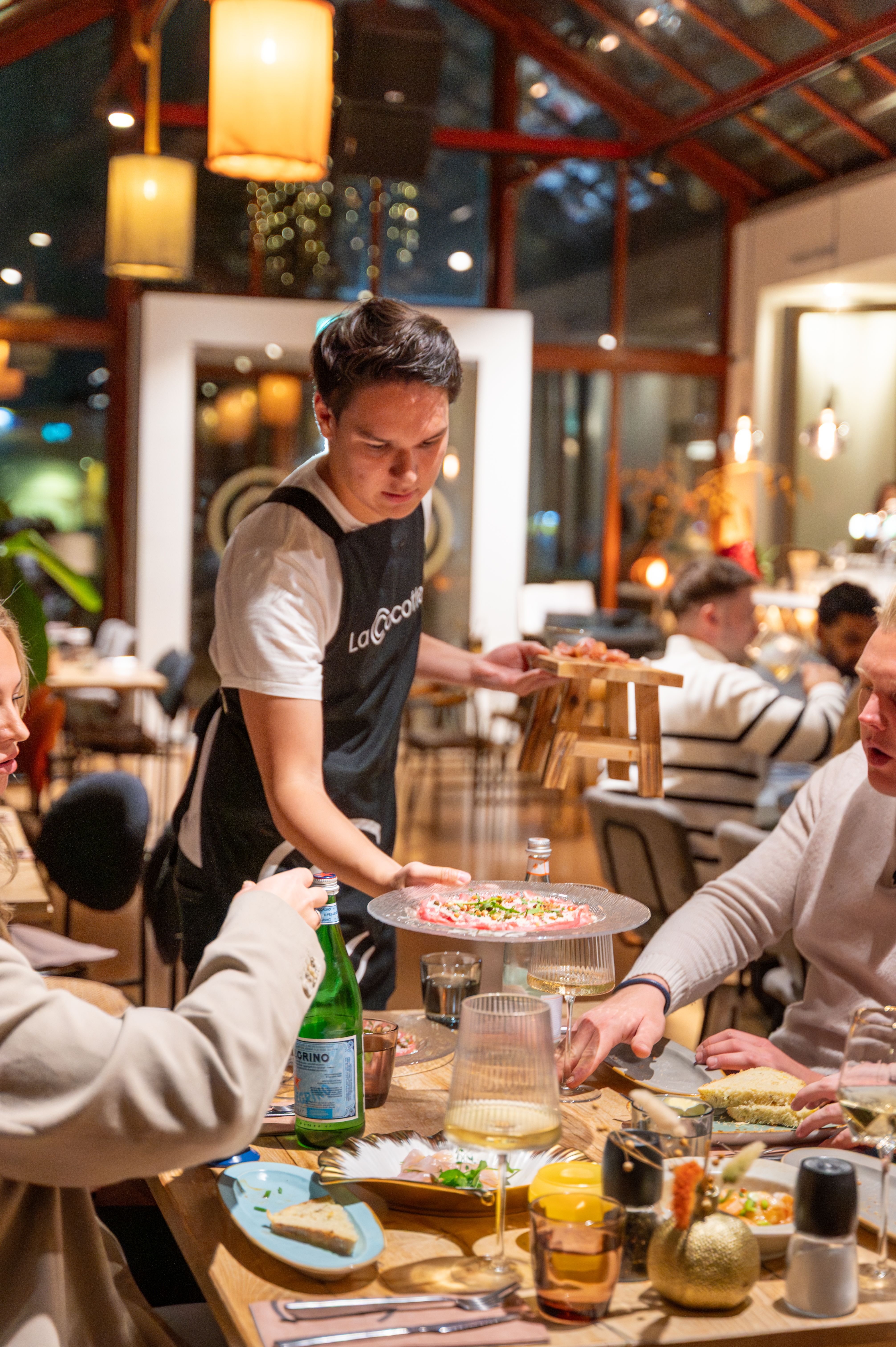 Lachende gasten aan tafel in de Kas tijdens speech in de Kas van 40 jarig huwelijk.