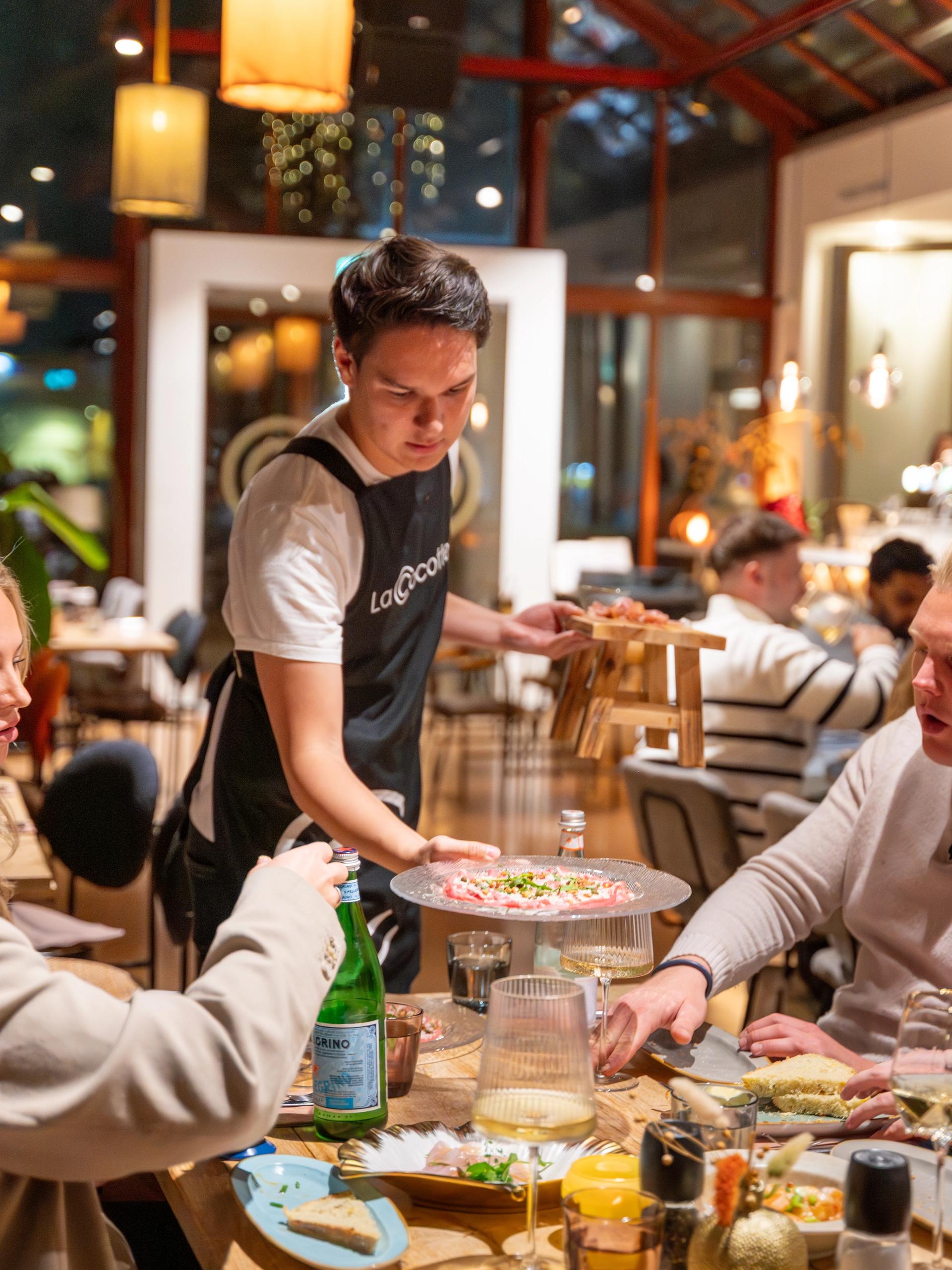 Lachende gasten aan tafel in de Kas tijdens speech in de Kas van 40 jarig huwelijk.