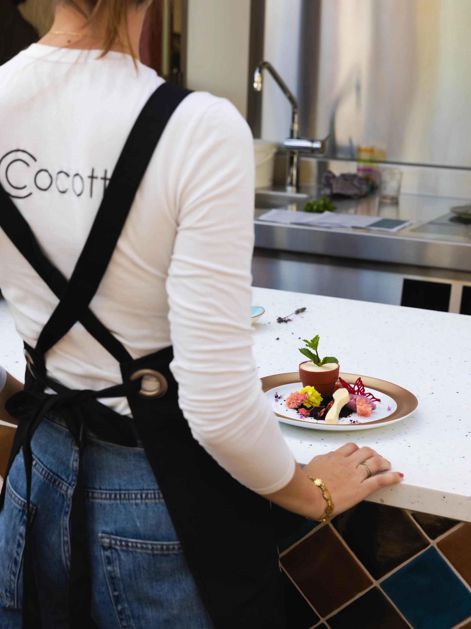Medewerker van La Cocotte aan de pas bij het dessert The Garden of La Cocotte, met bloemetjes en een chocoladen bloempotje