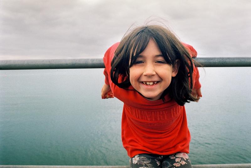 a colour photo of a young child in a red jumper smiling 