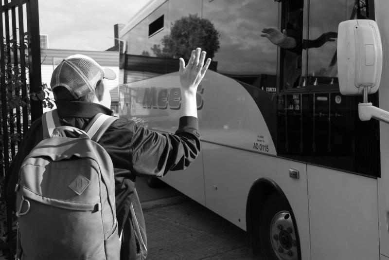 a boy waving to a bus driver