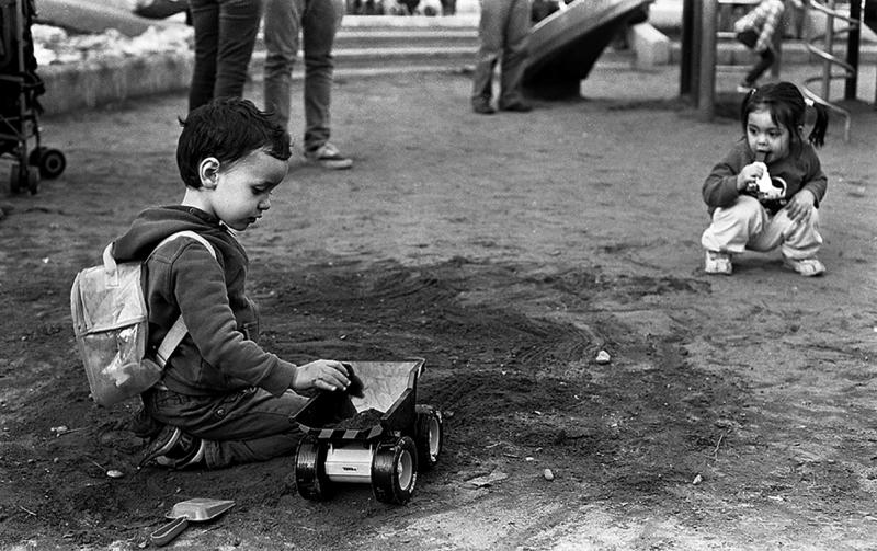 a black and white photo of two children playing with a tractor in the dirt