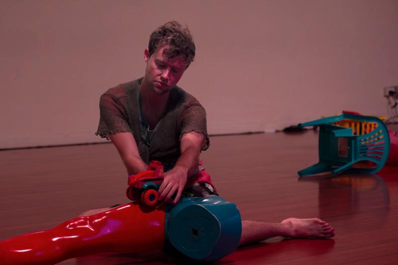 a performer sits on the floor playing with toys