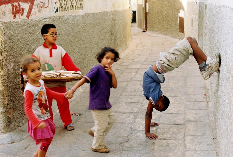 a colour photo of a child doing a handstand and children playing on the street in Morocco 